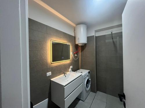 a bathroom with a sink and a washing machine at BlueWaveapartments 4 in Shëngjin