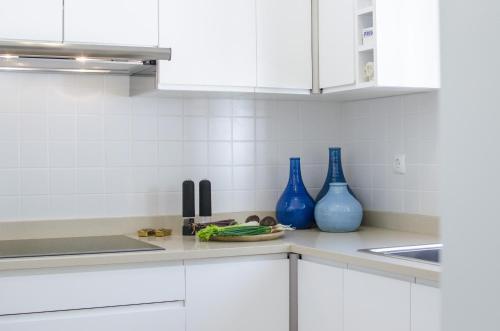 a kitchen with white cabinets and blue vases on the counter at Casa Caribe by Algarve Holidays in São Brás de Alportel