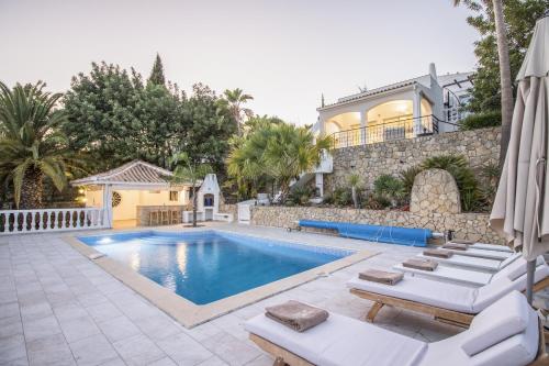 a swimming pool with lounge chairs and a house at Casa Caribe by Algarve Holidays in São Brás de Alportel