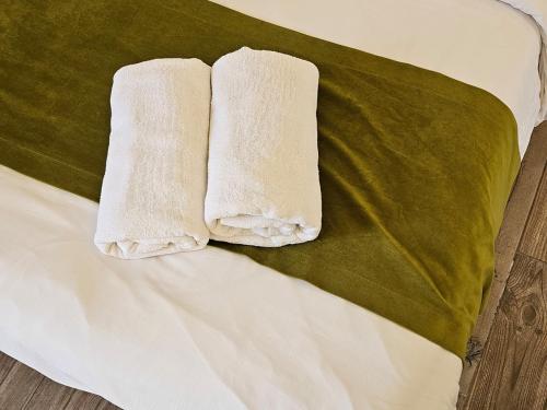 Zwei weiße Handtücher liegen auf einem Bett. in der Unterkunft Villajohn in Ad Dā‘ūq