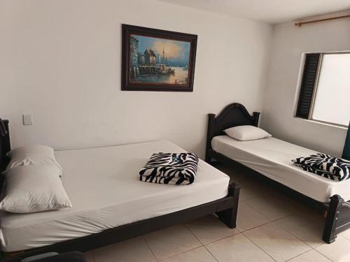 two beds in a room with a picture on the wall at Hotel Confort Boutique in Rionegro