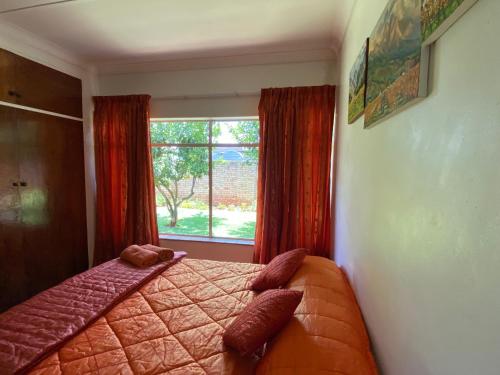 a bedroom with a bed and a window with red curtains at Highway Haven in Stilfontein