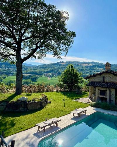 a swimming pool with two benches next to a house at Azzurro di Vallepietra in Camporotondo di Fiastrone