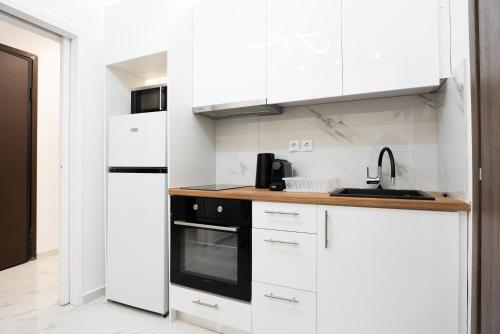 a kitchen with white cabinets and a black appliance at Syntagma Luxury Apartment in Athens