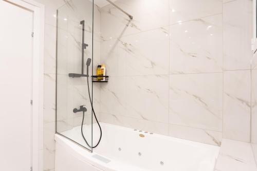 a white bathroom with a shower and a tub at Syntagma Luxury Apartment in Athens