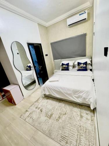 a bedroom with a large white bed with a mirror at Nimble Focus Apartment in Lagos