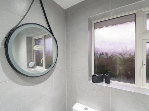 a white bathroom with a mirror and a window at Modern tyne & wear house in North Tyneside