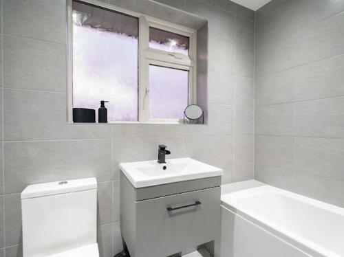 a bathroom with a sink and a toilet and a window at Modern tyne & wear house in North Tyneside