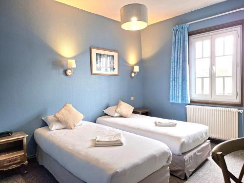 a room with two beds and a window at Hôtel Le Chantilly Deauville in Deauville