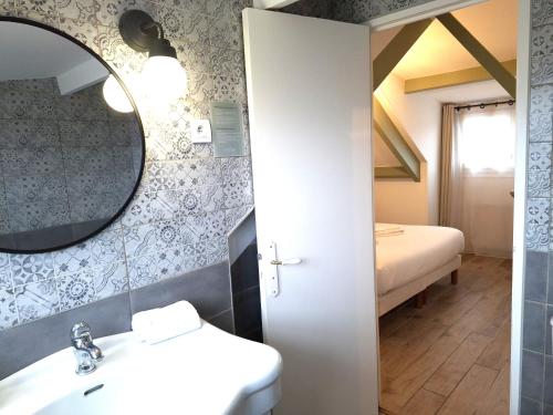 a bathroom with a sink and a mirror and a bed at Hôtel Le Chantilly Deauville in Deauville