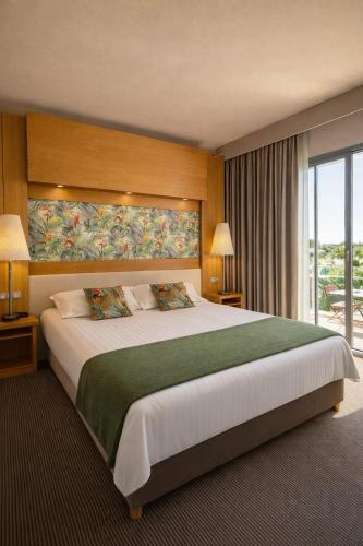 a bedroom with a large bed with a large window at Le Safari Hotel Restaurant in Carpentras