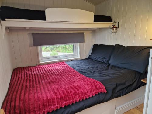 a bed in a small room with a red blanket at Bramblewick House Glamping in Longford
