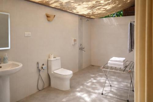 a bathroom with a toilet and a sink at Nature's Nest Goa in Molem