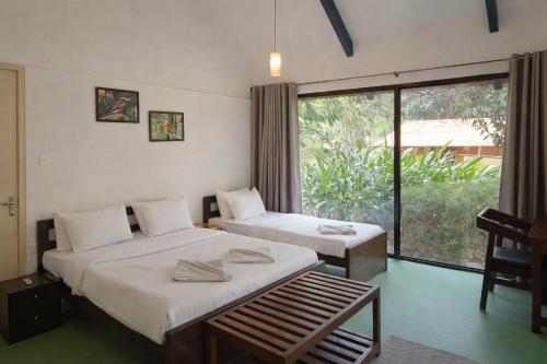 a bedroom with two beds and a large window at Nature's Nest Goa in Molem
