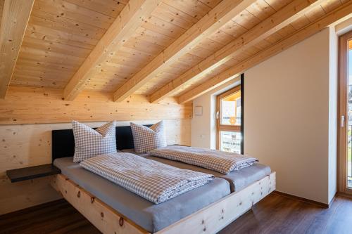two beds in a room with a wooden ceiling at Alpenrose in Obermaiselstein