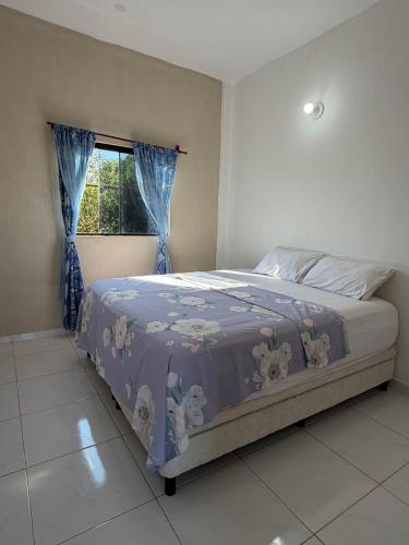 a bedroom with a bed with a purple comforter and a window at JG&A Home in Itauguá
