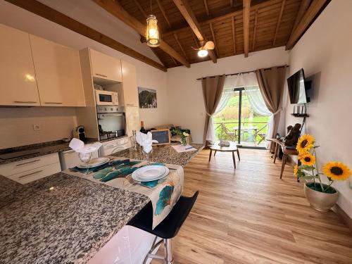 a kitchen and living room with a counter and a table at Casas da Quinta in Santa Cruz das Flores