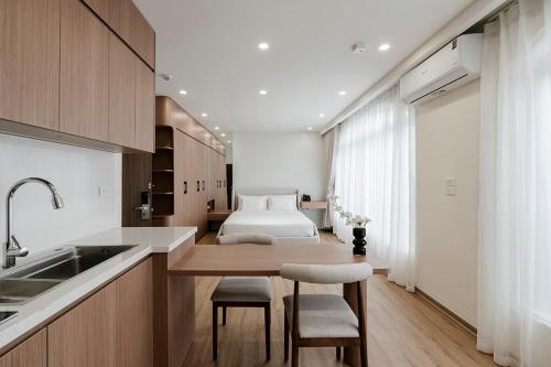 a kitchen with a table and a bed in the background at Residences A-25 in Hanoi