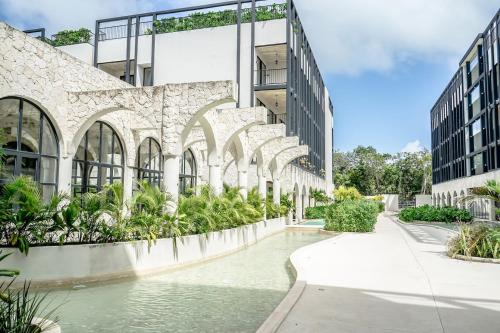 an external view of a building with water and plants at Jungle View Nest Selva Rooftop in Tulum