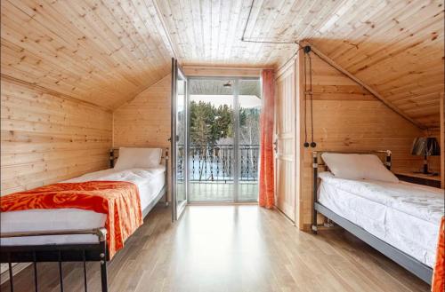 two beds in a wooden room with a balcony at SetAura Kazbegi in Kazbegi