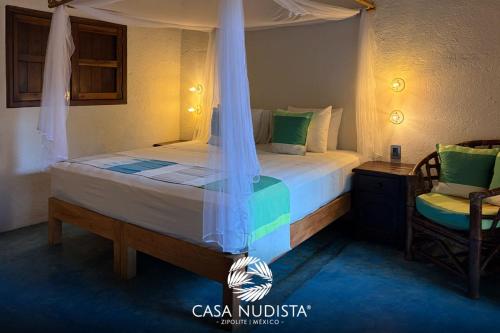 a bedroom with a bed and a chair at Casa Nudista - LGBT Hotel in Zipolite