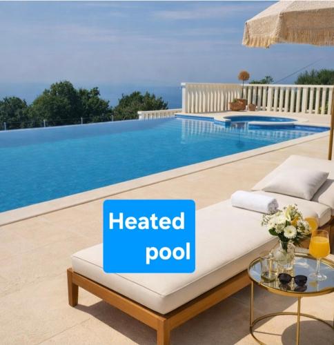 a heated pool in a villa with a bed and a table at Villa Conte in Podstrana