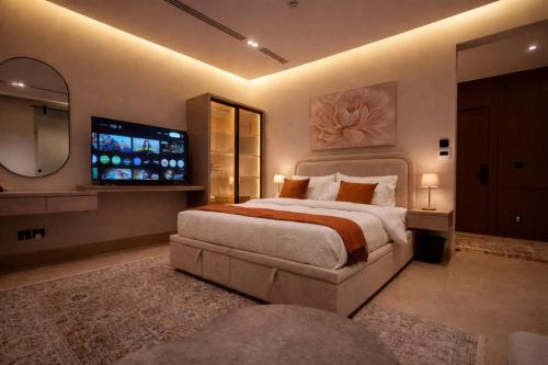 a bedroom with a large bed and a flat screen tv at Hanay Studio in Al Khobar