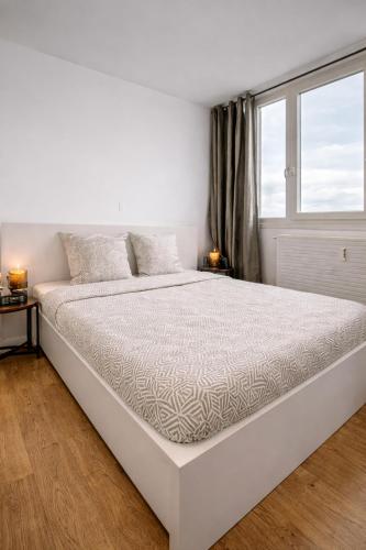a white bed in a white bedroom with a window at Beau duplex lumineux avec balcon in Chalon-sur-Saône