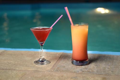 two cocktails sitting on a table next to a pool at Hotel Melikari in Skiros