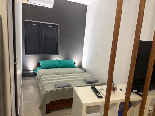 a small bedroom with a bed and a television at Le manga in Chiconi