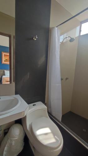 ein Badezimmer mit weißer Toilette und Waschbecken in der Unterkunft Hotel JORGE CHAVEZ in Trujillo