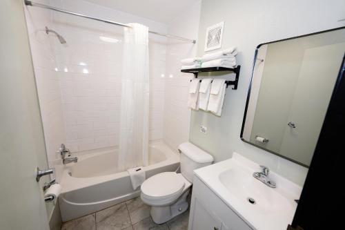 a white bathroom with a toilet and a sink at Scottish Inn Maggie Valley in Maggie Valley