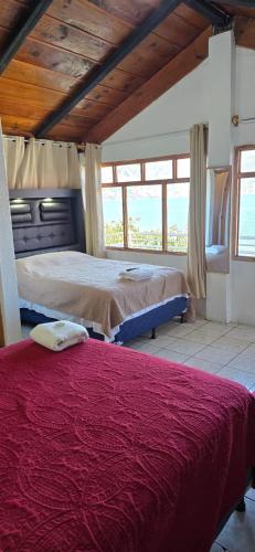 a bedroom with two beds in a room with windows at Hotel Victoria Atitlan in San Pedro La Laguna