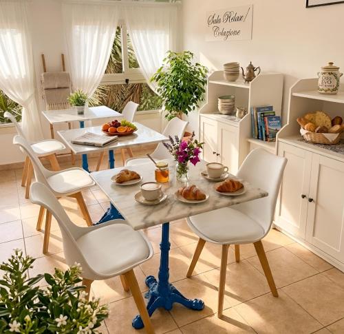 a kitchen with a table and chairs with food on it at Jacaranda Rooms in SantʼAntìoco