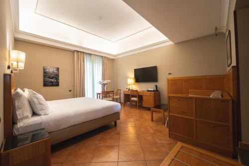 a bedroom with a bed and a desk and a television at Hotel Forum in Pompei