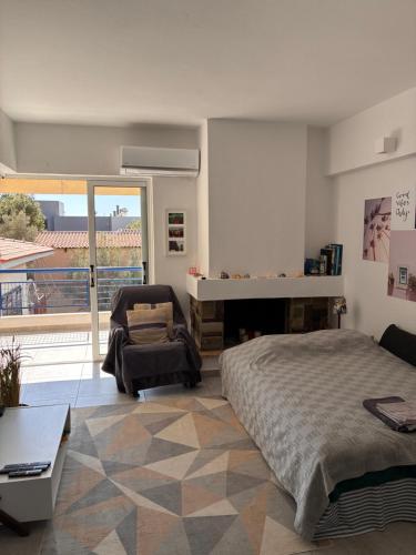 a bedroom with a bed and a chair and a balcony at Sparkling dream in Saronida