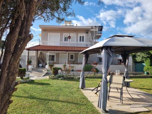 a table and chairs under an umbrella in front of a house at Isthmus Filoxenia in Isthmia