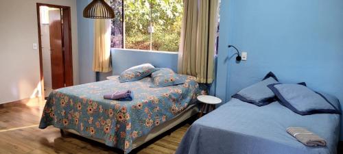 a blue bedroom with two beds and a window at REFUGIO Chacara ENTRE NÓS in Holambra
