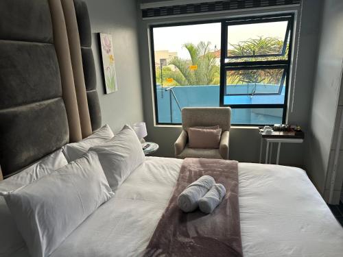 a bedroom with a white bed with a chair and a window at Kbros Guesthouse in Polokwane