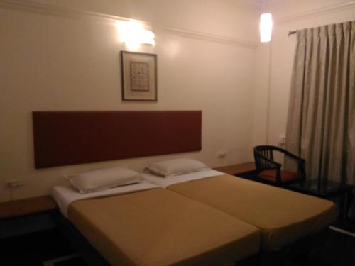 a bedroom with a bed with two pillows on it at Woody's in Bangalore