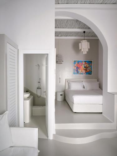 a white bedroom with a bed and a bathroom at Chiara Mykonos in Mikonos