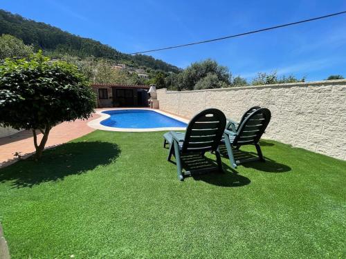 two chairs sitting on the grass near a swimming pool at Apartamento Río Bispo in Bueu