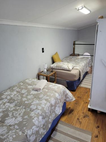 two beds in a small room with wooden floors at Dream Big Bougainvillea 2 bedroom cottage in Centurion