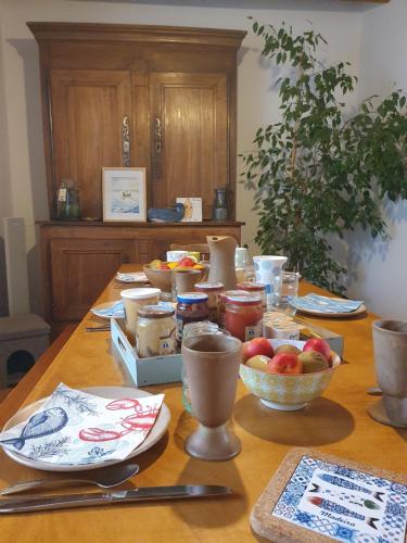 a wooden table with plates and bowls of fruit on it at Au chat qui pêche in Pléguien