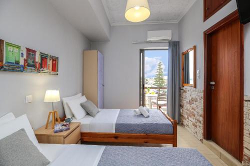 a hotel room with two beds and a window at Nefeli Rooms in Agia Marina Nea Kydonias