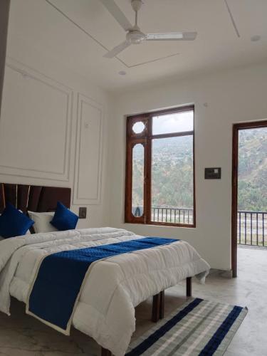 a bedroom with a bed with blue pillows and a window at Velley inn hotel & resort in Barkot