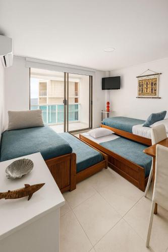 a bedroom with two beds and a table and a window at Coral Confort APTS San Andres in San Andrés