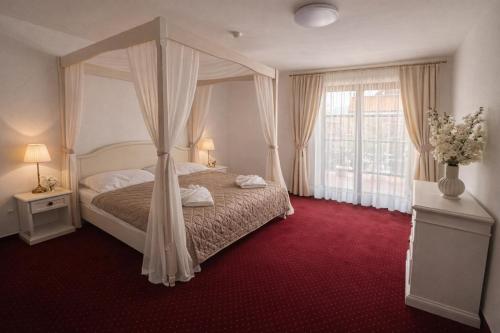 a bedroom with a canopy bed and a window at Hotel Sebastian u Hoffera in Modra
