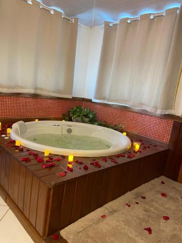 a bathroom with a tub with candles and red roses at Pousada Thetis in Arraial do Cabo