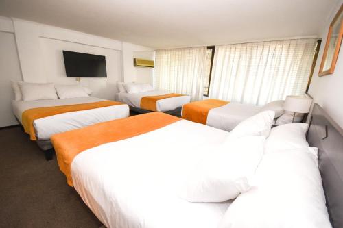 a hotel room with three beds and a flat screen tv at Hotel Casa Nogales in Santiago